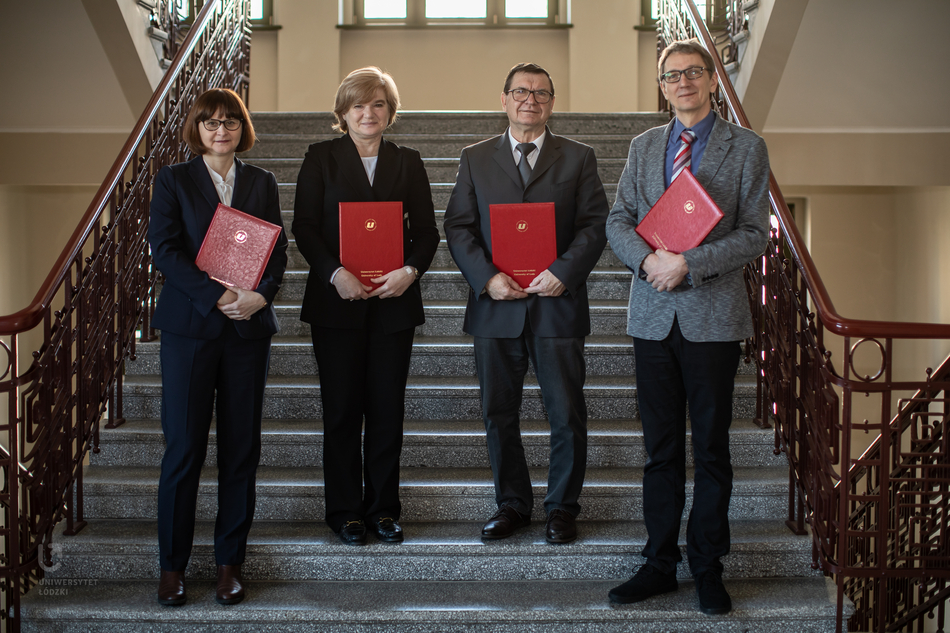 Cztery osoby na schodach z podpisanymi dokumentami